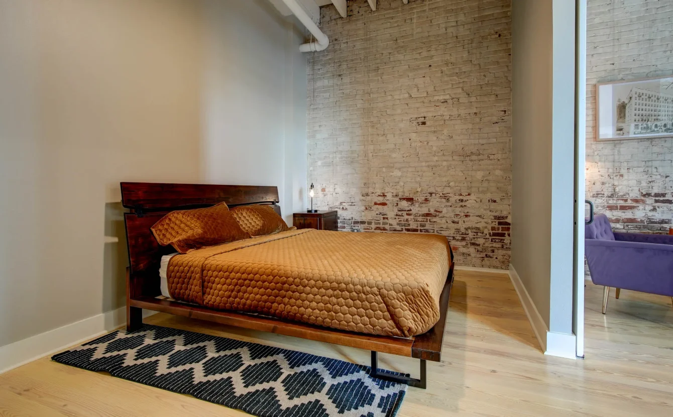 Bedroom with exposed brick and natural light at Lofts at Creek Street