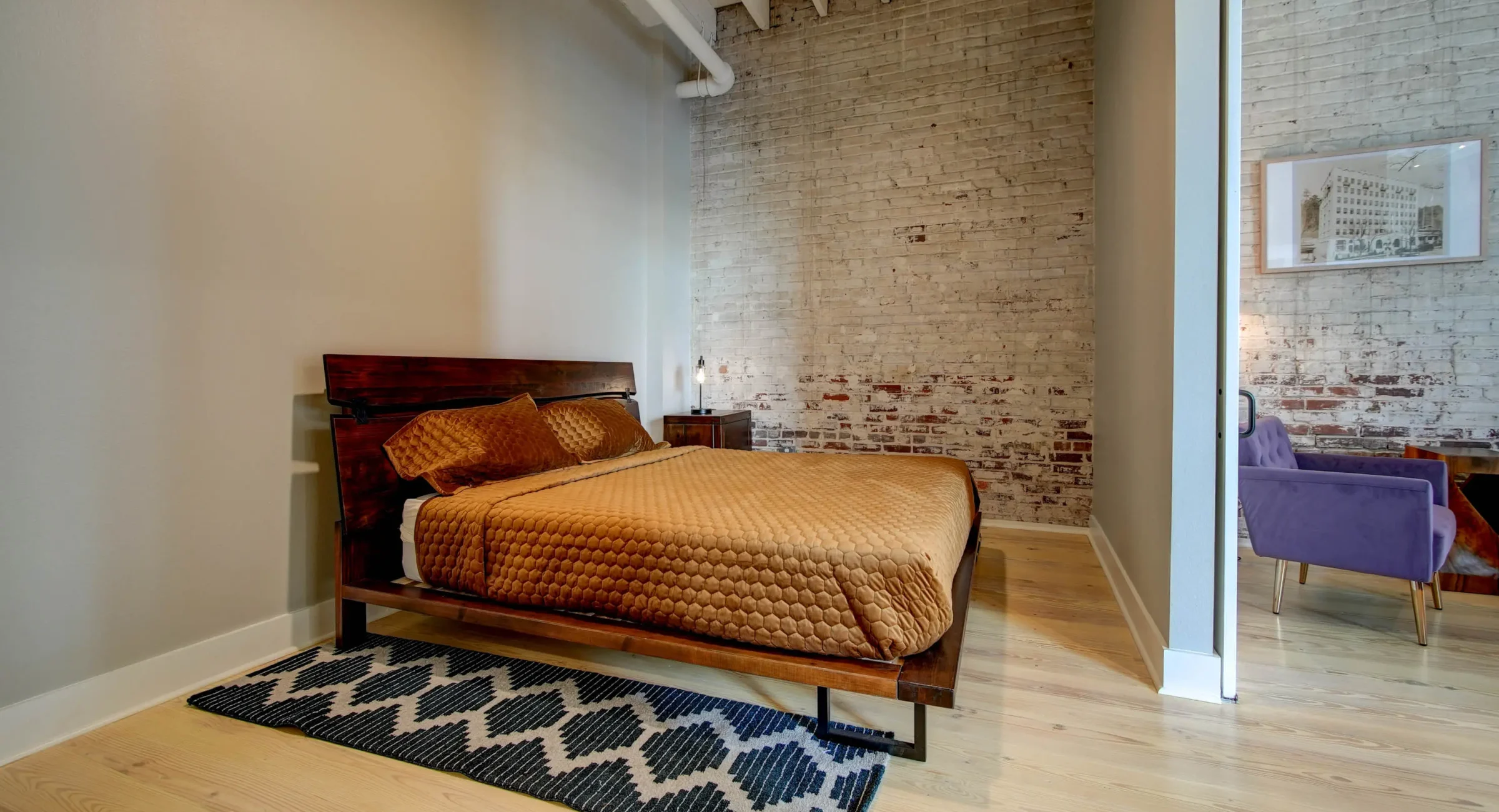 Bedroom with exposed brick and natural light at Lofts at Creek Street