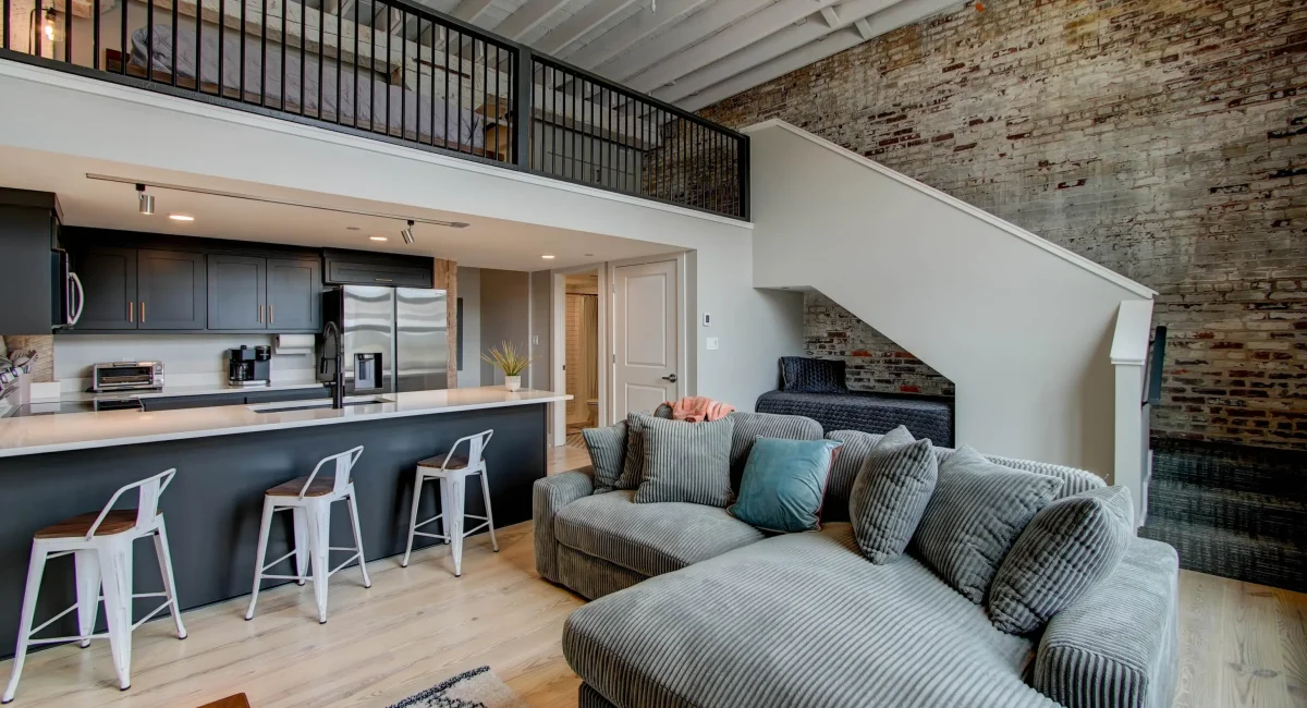 Open living room with staircase and loft sleeping area in historic Hot Springs loft