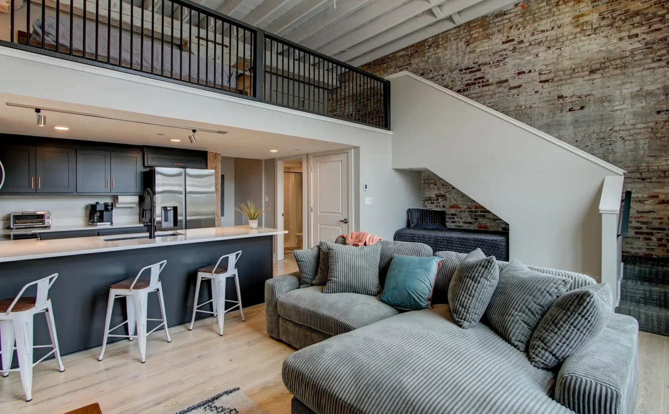 Open living room with staircase and loft sleeping area in historic Hot Springs loft