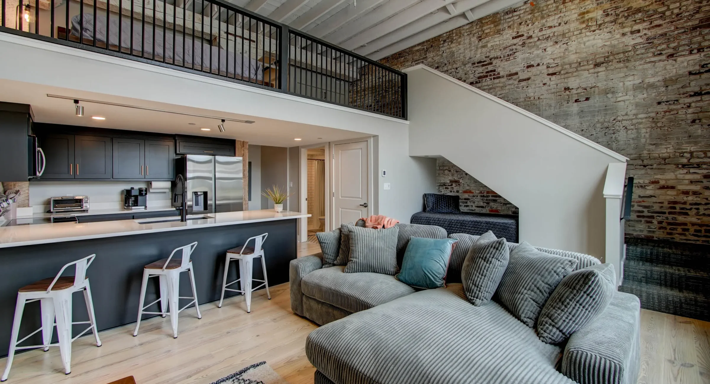 Open living room with staircase and loft sleeping area in historic Hot Springs loft