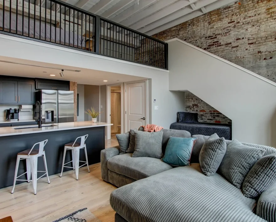 Open living room with staircase and loft sleeping area in historic Hot Springs loft