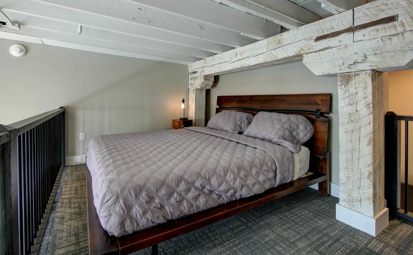 King bed with exposed beams in historic downtown Hot Springs loft