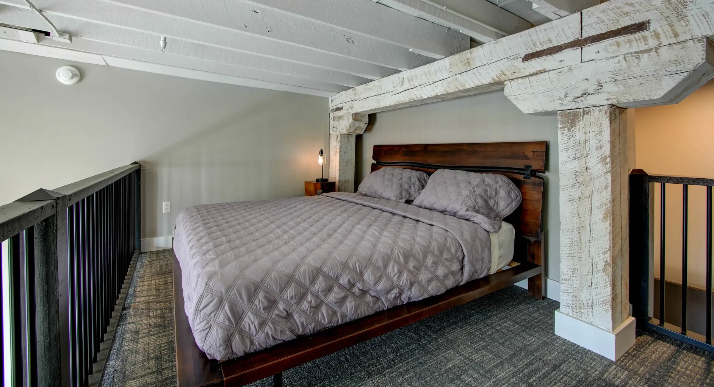 King bed with exposed beams in historic downtown Hot Springs loft