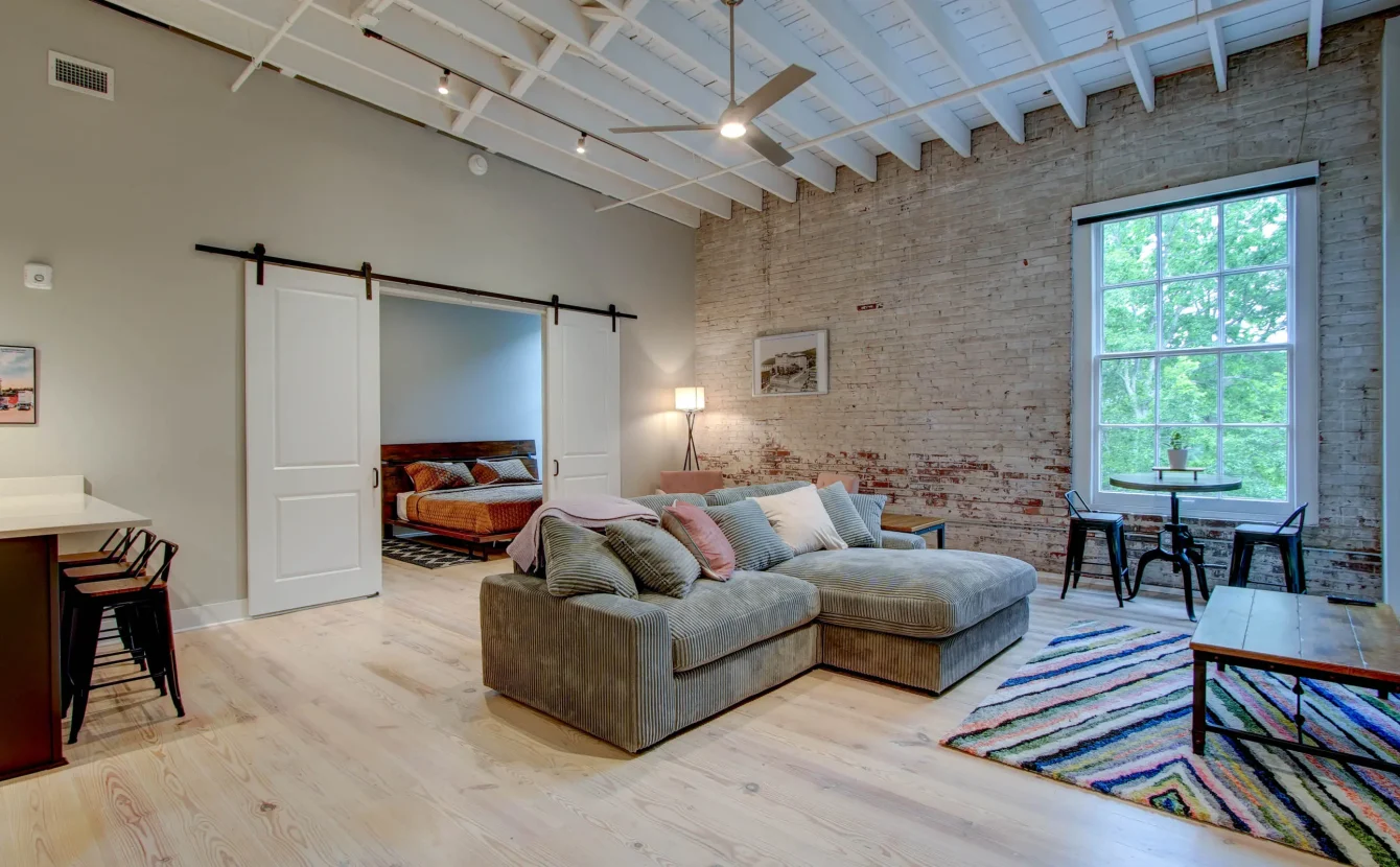 Open-concept living room with exposed brick in The Moody suite, Hot Springs